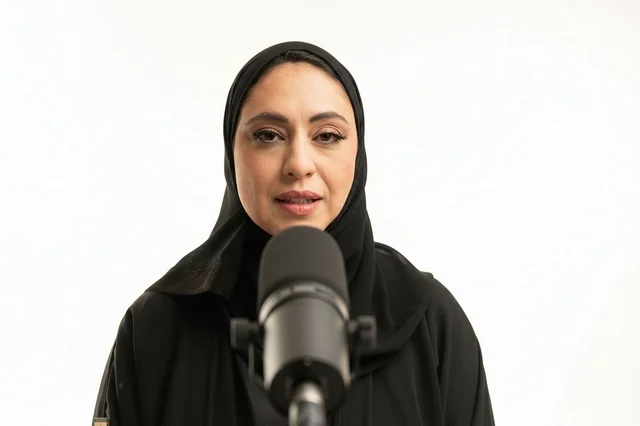 امرأة إماراتية تتحدث أمام ميكروفون في استوديو