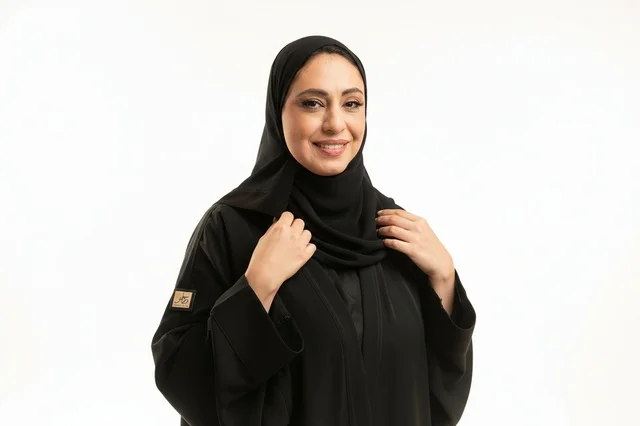 امرأة سعودية مبتسمة بالعباءة السوداء في الاستوديو