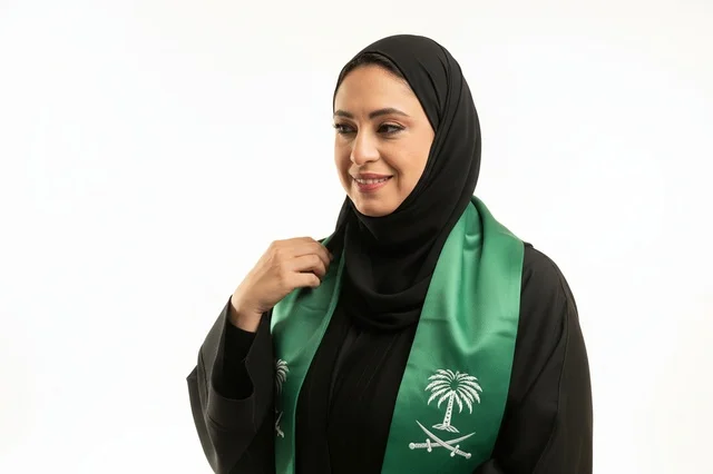 امرأة سعودية بالعباءة والوشاح الوطني السعودي