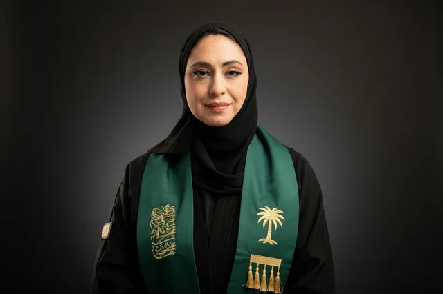 امرأة سعودية بالعباءة التقليدية ووشاح اليوم الوطني الأخضر