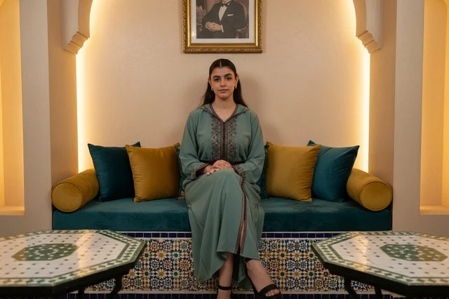 Moroccan Woman in Traditional Djellaba Sitting in Salon