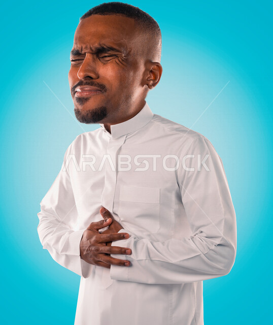 بورتريه لرجل عربي خليجي سعودي يضع يديه على بطنه ،ايماءات وجه ويدين تدل على الالم والوجع ، اصابة في منطقة البطن ، الام في المعدة ، اضطرابات معوية