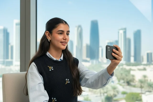 Saudi Woman Using Smartphone in Modern Office Skyline