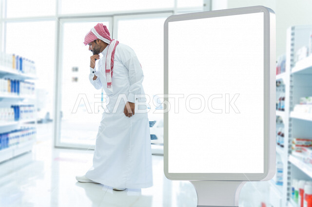 رجل عربي خليجي سعودي داخل الصيدلية ، تفقد المنتجات الطبية ، طلب الادوية الموجودة في الوصفة الطبية ، شراء الادوية والمستلزمات الطبية ، لوحة يونيبول إعلانية تجارية مضيئة بيضاء ، إعلانات دعائية طبية ، موك أب لوحة إعلانية 