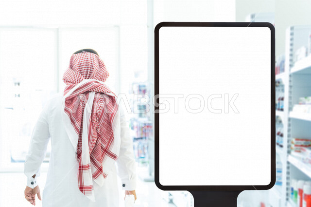 رجل عربي خليجي سعودي داخل الصيدلية ، تفقد المنتجات الطبية ، طلب الادوية الموجودة في الوصفة الطبية ، شراء الادوية والمستلزمات الطبية ، لوحة يونيبول إعلانية تجارية مضيئة بيضاء ، إعلانات دعائية طبية ، موك أب لوحة إعلانية 