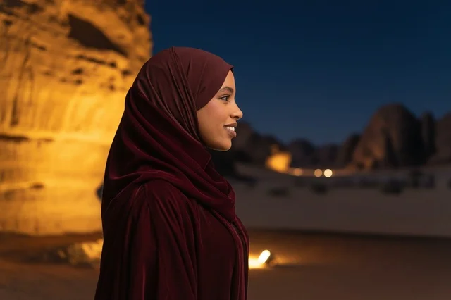 امرأة سعودية بعباءة مخملية في الصحراء ليلاً