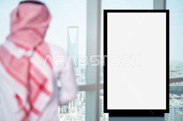 صورة من الخلف لرجل عربي خليجي سعودي يقف بجانب لوحة يونيبول إعلانية تجارية مضيئة بيضاء في الشركة ، عقد صفقات تجارية إعلانية ، لوحة إعلانية فنية تجارية ، عروض ترويجية و تسويقية ، موك أب لوحة إعلانية 