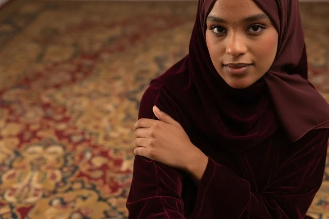 Saudi Woman in Burgundy Velvet Abaya on Carpet