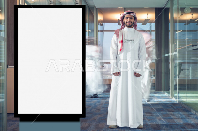 رجل عربي خليجي سعودي يقف بجانب لوحة يونيبول إعلانية تجارية مضيئة بيضاء في الشركة ، عقد صفقات تجارية إعلانية ، لوحة إعلانية فنية تجارية ، عروض ترويجية و تسويقية ، دعاية و إعلان ، موك أب لوحة إعلانية 