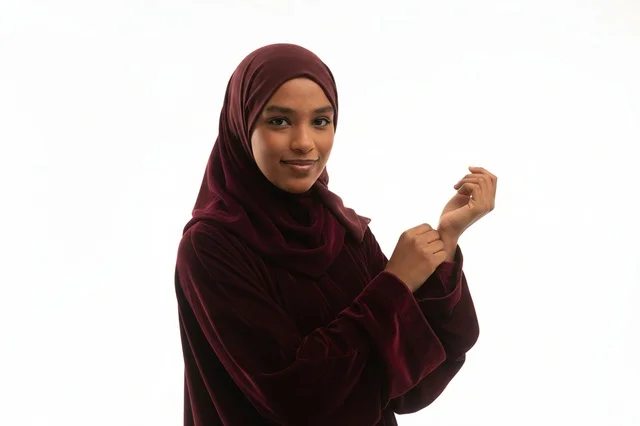 An African woman in a hijab and a burgundy velvet abaya.