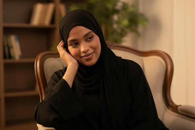 Arab Woman in Black Abaya Sitting in Armchair Indoor