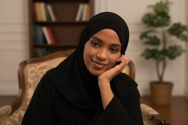 امرأة سعودية بالعباءة السوداء تجلس في مكتبة