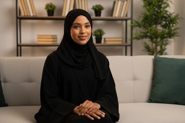 امرأة إماراتية بالعباءة السوداء تجلس على الأريكة