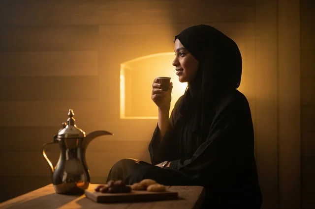 امرأة سعودية بالعباءة تشرب القهوة العربية