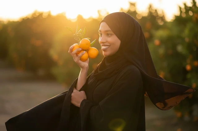 Saudi Woman with Oranges in Orchard at Sunset