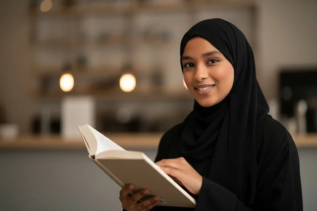 امرأة سعودية بالعباءة تقرأ كتاباً في الداخل