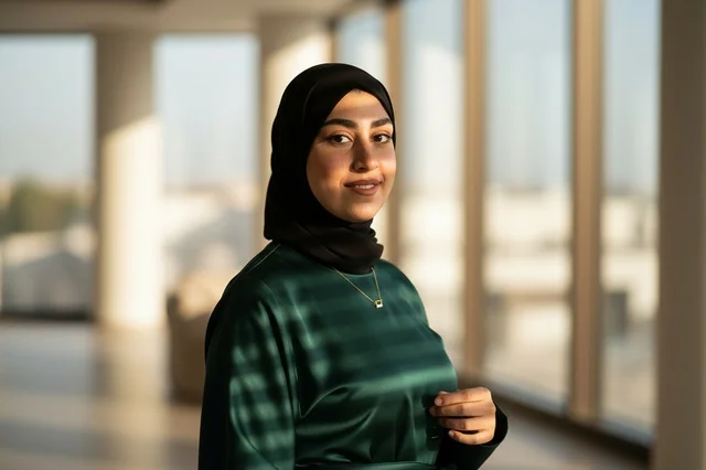امرأة سعودية محجبة تقف داخل مكتب حديث