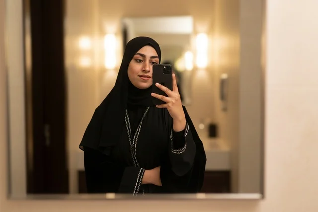 امرأة سعودية بالعباءة السوداء تلتقط سيلفي في المرآة