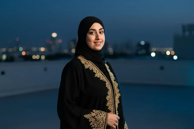 امرأة إماراتية بالعباءة على سطح مبنى مع أضواء المدينة