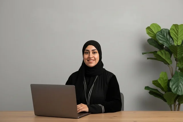 امرأة سعودية بالعباءة تعمل على اللابتوب في المكتب