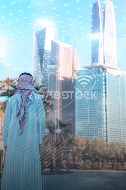 تصوير من الخلف لشاب عربي خليجي سعودي ينظر الى ناطحات السحاب ، مطور شبكة الحاسوب والانظمة البرمجية ، التطور العمراني ، النهضة التكنولوجية ، رؤية 2030 ، خلفية لشبكة التكنولوجيا وايقونات الحاسوب