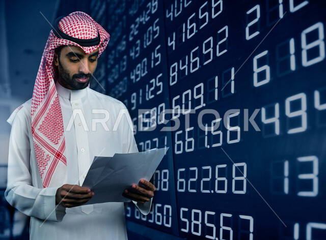 رجل عربي خليجي سعودي يحمل بيده مجموعة من الاوراق ، تقارير عن السوق المالي ، متابعة مخطط الرسم البياني للنمو الاقتصادي ، سوق الاوراق المالية ، النجاح في التداول المالي ، مراقبة الاقتصاد والمعلومات المالية ، الاستثمار المالي ،خلفية لوحة بورصة رقمية 