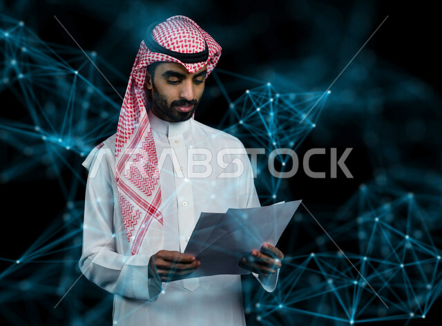 رجل عربي خليجي سعودي يحمل بيده مجموعة من الاوراق  ، تقارير خاصة بالعمل ، بحث علمي عن التكنولوجيا الرقمية ، مفهوم الاتصال والويب ، تكنولوجيا الاعمال ، خلفية لاشكال هندسية للاتصال والتكنولوجيا