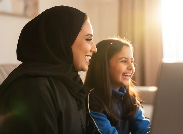 Saudi Mother and Daughter Using Laptop at Home