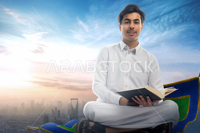 طالب جامعي عربي خليجي سعودي يحمل بيده الكتاب و يجلس على السجادة الطائرة فوق مدينة الرياض  ، رحلة تعليمية ، مستقبل تعليمي ساحر ، تحقيق الاهداف والطموحات ، التعليم الاكاديمي في المملكة العربية السعودية 
