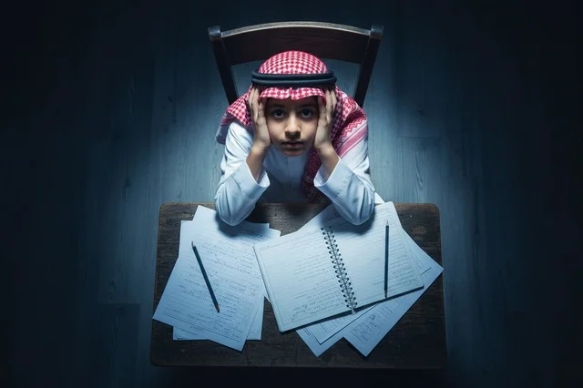 Saudi Boy in Traditional Dress Studying at Desk
