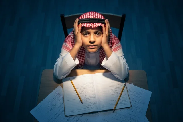طالب سعودي بالزي التقليدي يذاكر على المكتب