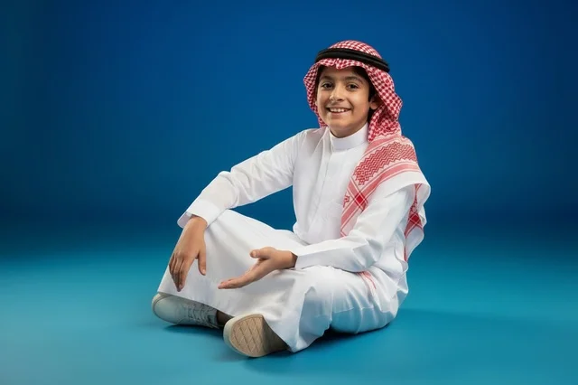 طفل سعودي بالزي التقليدي على خلفية زرقاء