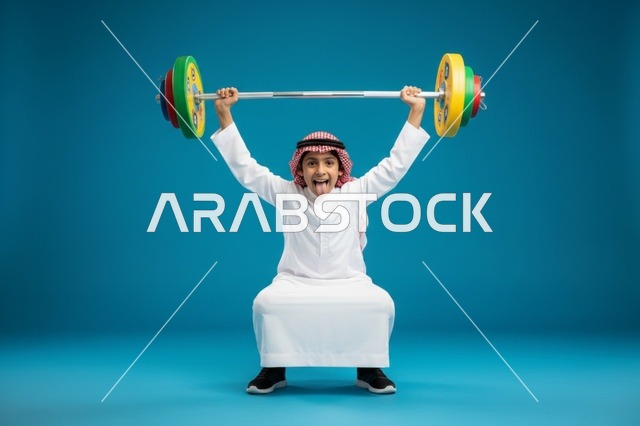 طفل سعودي يرفع الأثقال بالثوب والشماغ التقليدي