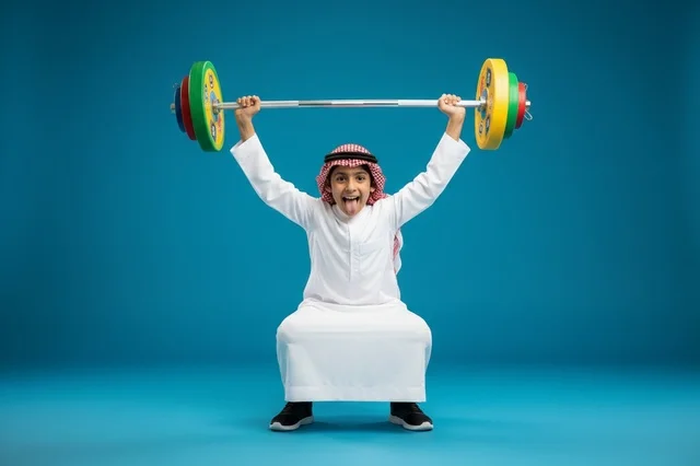 Saudi Boy Lifting Barbell in Traditional Dress Thobe