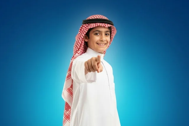 طفل سعودي بالزي التقليدي يشير بإصبعه