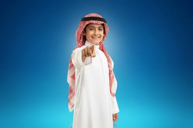 طفل سعودي بالثوب التقليدي يشير للكاميرا