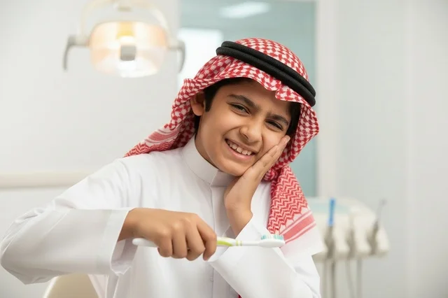 فتى سعودي يعاني من ألم الأسنان في عيادة طبية