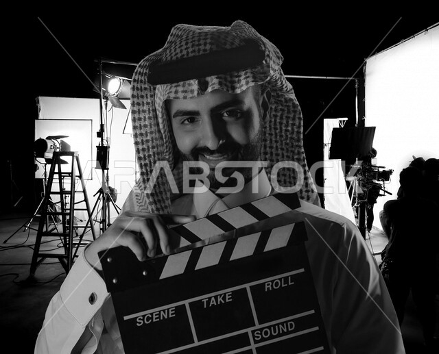 رجل عربي سعودي خليجي داخل موقع التصوير يحمل بيده لوح تصوير ، إخراج المسلسلات والأفلام ، الاشراف على طاقم التمثيل والعمل ، متابعة السيناريو والحوار ، التصوير السينيمائي 