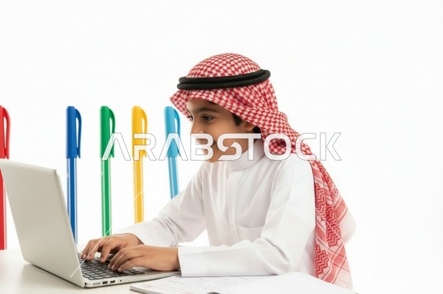 طفل سعودي يستخدم الحاسوب المحمول بالزي التقليدي