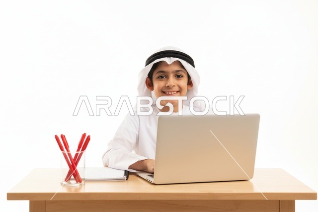 طفل إماراتي يستخدم الحاسوب المحمول على خلفية بيضاء