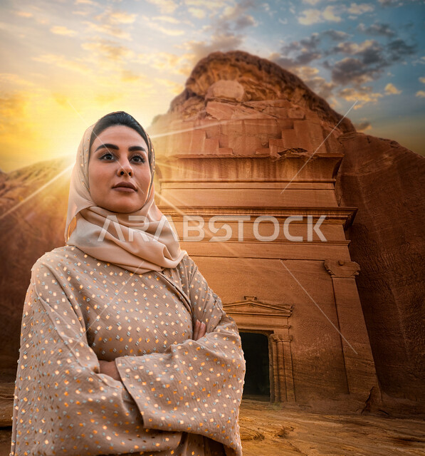 A Gulf Arab woman standing with folded hands in front of the rock formations of Madin Saleh in Al-Ula, Saudi Arabia, a Saudi tourist in the city of Al-Hajar in northwest Saudi Arabia