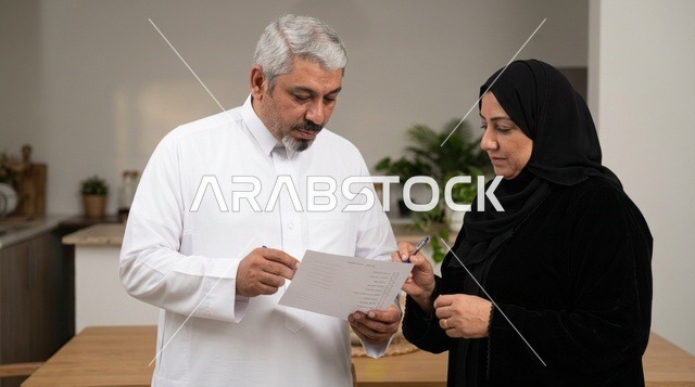 زوجان سعوديان يراجعان وثائق في مطبخ المنزل