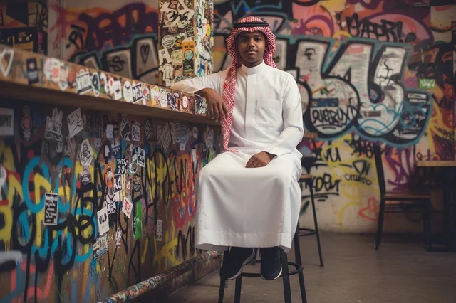 رجل سعودي بالزي التقليدي أمام جدار فن الجرافيتي