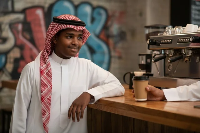 Saudi Man in Traditional Thobe at Coffee Shop Counter