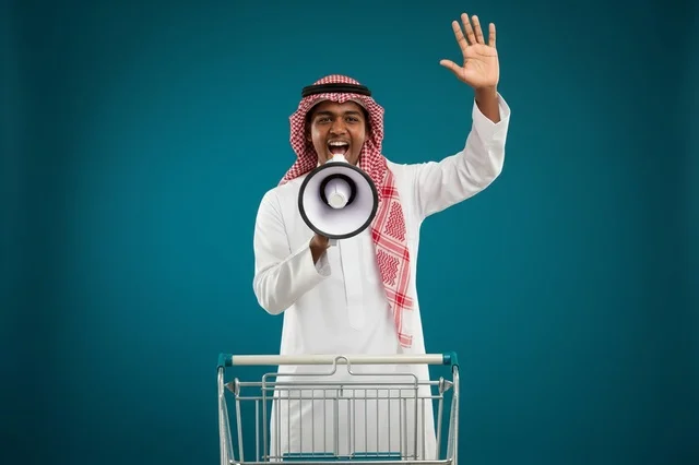 رجل سعودي مع مكبر صوت وعربة تسوق