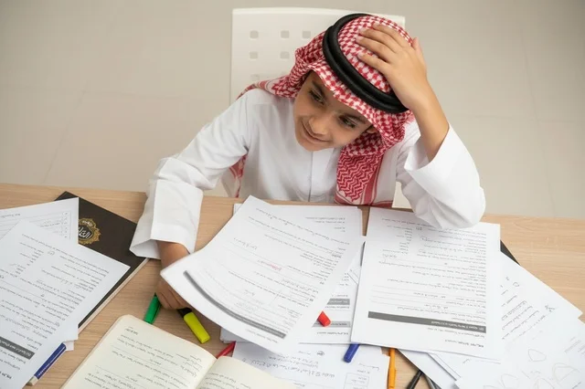 Saudi Boy in Traditional Thobe Studying at Desk