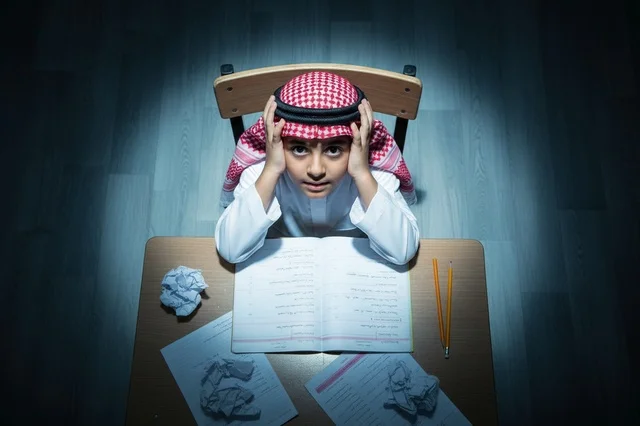 Saudi Boy Student Studying at Desk under Spotlight