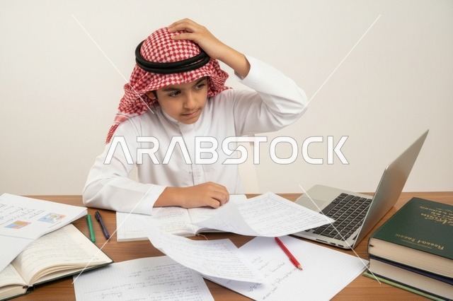 طالب سعودي يدرس باستخدام المحمول والأوراق المدرسية