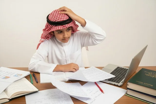 Saudi Boy Student Studying With Laptop and Papers