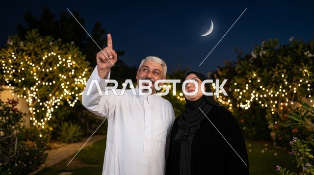 زوجان سعوديان ينظران إلى هلال العيد في حديقة ليلية